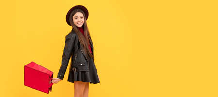 cheerful stylish teen child shopping. kid in hat hold shopping bag. autumn season trends. Banner of shopping child girl, studio poster header with copy space.の写真素材