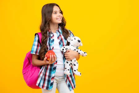 School girl hold toy. School children with favorite toys on yellow isolated background. Childhood...