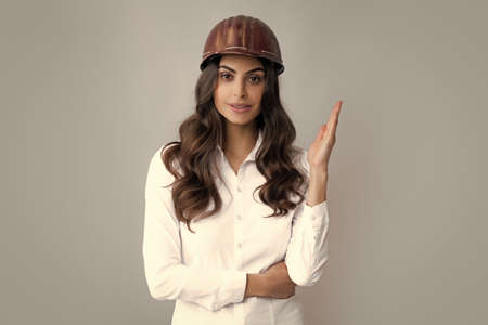 Positive woman in protective helmet isolated on grey background. Architect woman wear helmet and...