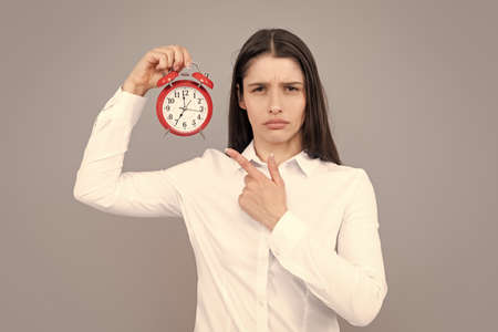 Surprised woman holding alarm watch. Isolated portrait.