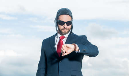 businessman in suit and pilot hat checking timeの写真素材