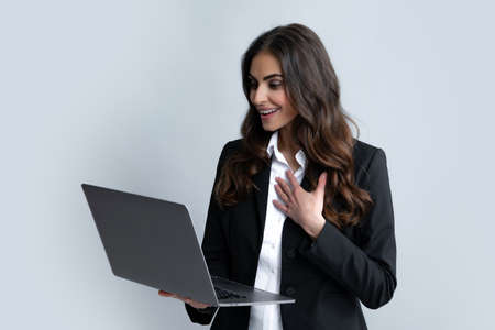 Blogging chatting woman. Young beautiful female teacher or happy student isolated on gray studio background. Portrait of college student with laptop. Woman working on laptop, freelance.の写真素材