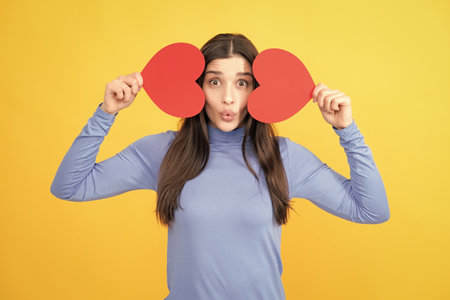 Beautiful amazing woman cuddle paper card heart shape, dreamy isolated on yellow background. Love concept.の写真素材