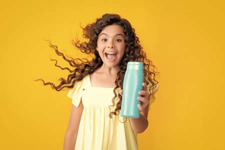 Child with shampoo conditioner. Daily cosmetic care. Teenager hold bottle of hair and skin care. Beauty health and cosmetics. Excited teenager, glad amazed and overjoyed emotions.の写真素材