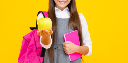 Child girl eating an apple over isolated yellow background. Tennager with fruit.の写真素材