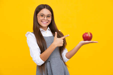 Fresh apple. Teenager girl hold apples on yellow isolated studio background. Child nutrition. Happy girl face, positive and smiling emotions.の写真素材