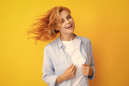 Redhead woman with movement hair. Studio shot of carefree redhead woman smiles cheerfully isolated...