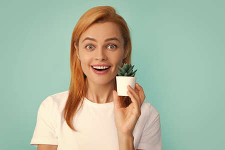 Emotional funny cute woman girl with a small cactus. Closeup face portrait isolated on blue background.の写真素材