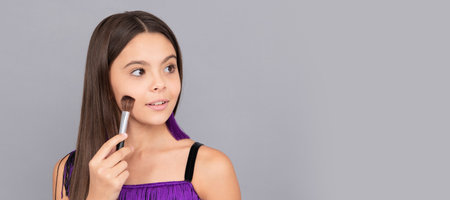 Make-up designer apply face powder with makeup brush grey background. Cosmetics for teenager child, poster design. Beauty kids makeup, banner with copy space.の写真素材