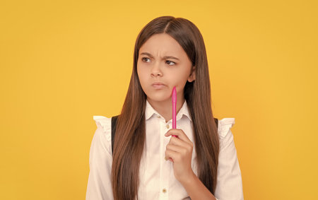 Develop new thinking. Thoughtful girl child yellow background. School education. Keep thinkingの写真素材
