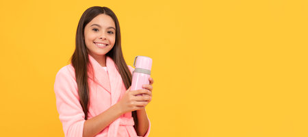 happy teen girl in home terry bathrobe with flask bottle, morning. Horizontal poster of isolated child face, banner header, copy space.の写真素材