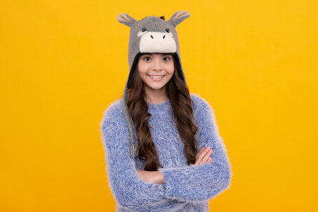 Teenager girl with winter hat over isolated yellow background. Winter christmas holidays, new year...