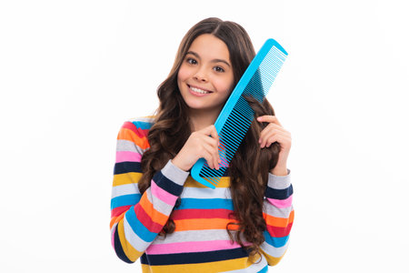 Teenager girl with long hair holding comb hairbrush for combing, beauty. Conditioner shampoo hair. Beauty kids salon. Child hairstyle. Happy girl face, positive and smiling emotions.の写真素材