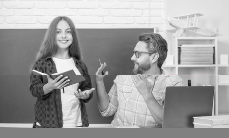 father and child study at school with book and laptop on blackboard background, education online.の写真素材