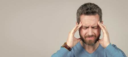 mature man with beard suffer from headahce on grey background, health. Man face portrait, banner with copy space.の写真素材