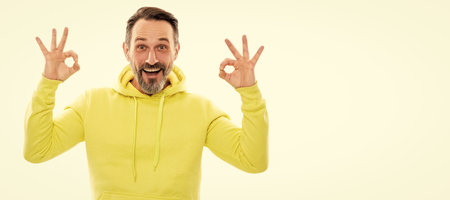 handsome mature man with beard and moustache in hoody isolated on white show ok gesture, perfection. Man face portrait, banner with copy space.の写真素材