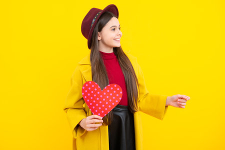 Happy teenager portrait. Lovely child teen girl with shape heart love holiday and valentine symbol. Valentine or birthday day. Gift heart present. Smiling girl.の写真素材