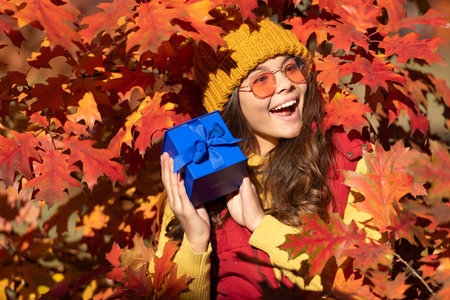 amazed child with present box on autumn leaves background