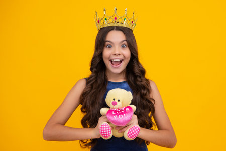 Birthday kids prom party. Teen child in queen crown isolated on yellow background. Princess girl in tiara. Teenage girl wear diadem. Happy girl face, positive and smiling emotions.の写真素材