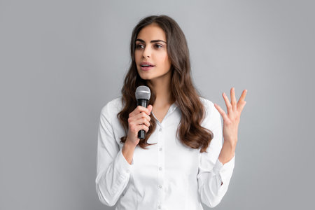 Beautiful business woman is speaking on conference. Young business woman talking with mic. Woman talking with microphone. Communication and information concept.の写真素材