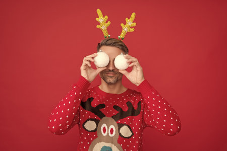 smiling man in winter sweater and party antlers. guy hold xmas decoration ballsの写真素材