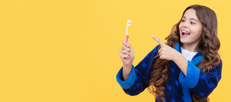 look here. child in pajama do morning routine. dental care. healthy beautiful smile. Banner of child girl with teeth brush, studio portrait, header with copy space.の写真素材