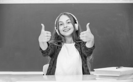 happy kid with earphones at blackboard showing thumb up, ebookの写真素材