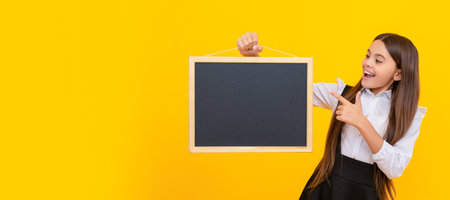 happy kid in uniform point finger on school blackboard for copy space, advert. Banner of school girl...