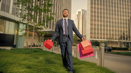 confident entrepreneur in suit holding shopping bag and giftbox outside the office, discount.の写真素材