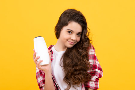 Child teen girl with shampoos conditioners and shower gel. Long hair care of teenager. Presenting cosmetic product, shampoo bottle. Happy teenager, positive and smiling emotions of teen girl.の写真素材
