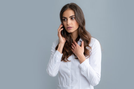 Serious woman with smart phone. Young woman with mobile phone. Businesswoman with smartphone on grey background.の写真素材