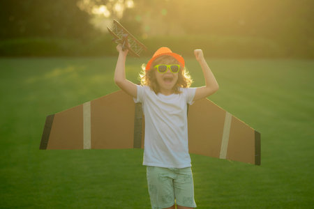 The concept of child kindness and childhood. Kid playing with toy airplane and dreaming future. Happy boy pilot play with airplane outdoors.の写真素材
