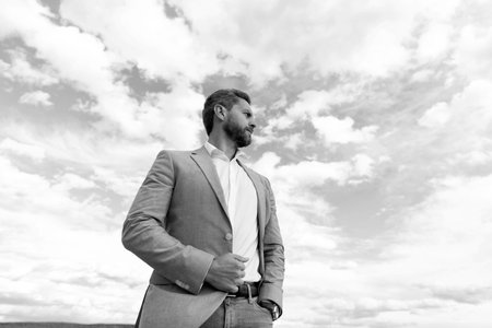 handsome mature man businessman in formal suit check time on wristwatch on sky background, successの写真素材
