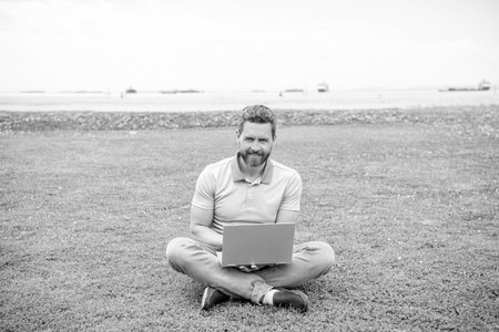 happy guy check email on computer relaxing on grass, modern life