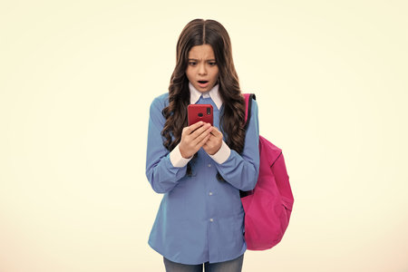 Excited face. Teen school student girl hold backpack use mobile cell phone on white background....