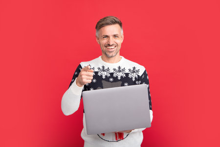Man in Christmas santa sweater, winter holiday, christmas background. Man with laptop.の写真素材