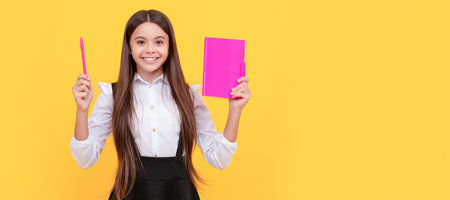 Ready back to school. Happy kid hold pen and book. Portrait of schoolgirl student, studio banner header. School child face, copyspace.の写真素材