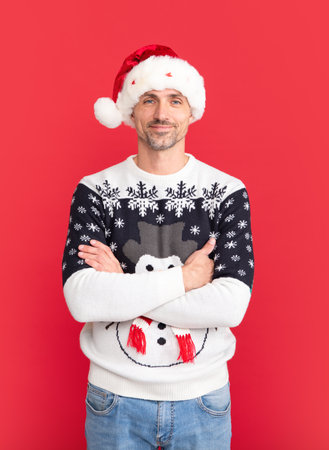 Portrait of middle aged man in sweater isolated over red background. Concept of holidays, happiness, emotions and Christmas celebration.の写真素材