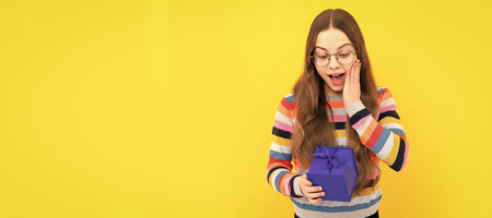 surprised child in eyeglasses hold gift box for birthday, birthday surprise. Child with birthday gift, horizontal poster. Banner header with copy space.の写真素材