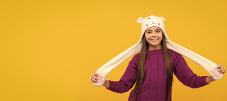 Winter child isolated portrait. cheerful kid in earflap hat on yellow background, fashion. Banner of...