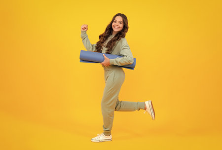 Teenage girl dressed in sports uniform, posing in the studio. Child in a posh stylish sports suit in a hoodie with a hood. Advertising sportswear and yoga wear. Run and jump.の写真素材
