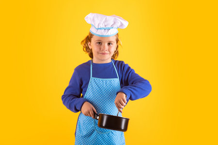 Kid chef cook with cooking pot stockpot. Chef child preparing healthy food. Studio portrait of child with chef hats.の写真素材