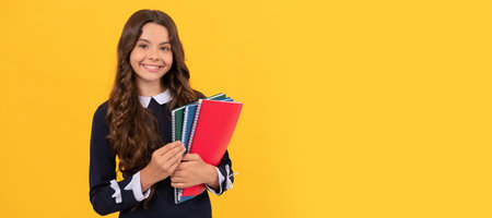 happy child hold school copybooks for homework studying on yellow background, school. Banner of...
