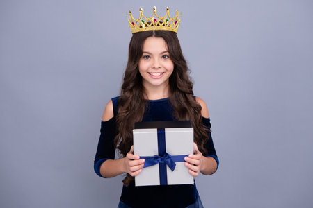 Child princess in crown. Child with gift present box on isolated background. Presents for birthday,...