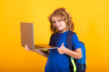 School child using laptop computer. School and kids. Cute blonde child with a book learning. Knowledge day.の写真素材