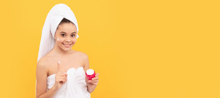 Kids facial treatment, cosmetology and spa, happy teen girl in shower towel apply facial cream. thumb up. Cosmetics and skin care for teenager child, poster design. Beauty kid girl banner.の写真素材
