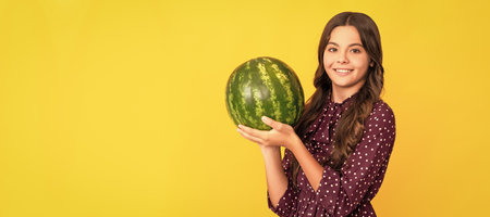 happy kid holding fresh ripe water melon fruit on yellow background. Summer girl portrait with...