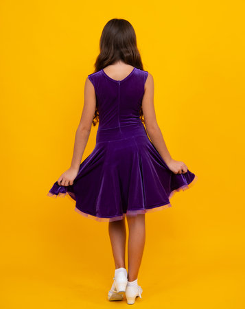 Full length of teenager child in ball dress. Back view of young graceful teenager child in dress isolated on yellow background.の写真素材