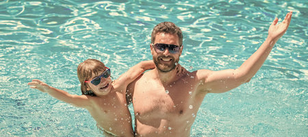 Father and son in swimming pool, banner with copy space. happy family of daddy and child having fun in summer swimming pool, free timeの写真素材