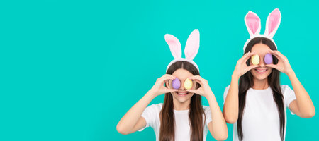 Mother and daughter child banner, copy space, isolated background. funny easter family of mother and daughter in bunny ears hold painted eggs, easter egg hunt.の写真素材